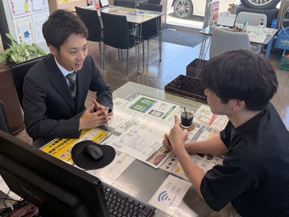 スタッフがお客様と一緒にパソコンの画面を見ながら中古車を探している様子
