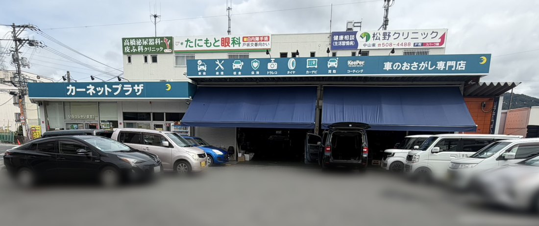 カーネットプラザ広島東店の店先。「車のおさがし専門店」の看板と整備ピット