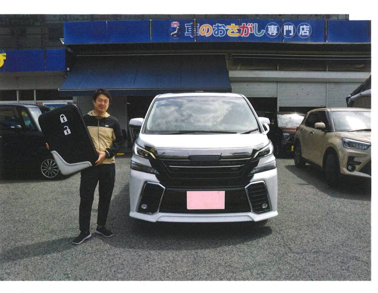 納車されたヴェルファイアとお客様。店の看板が写っている